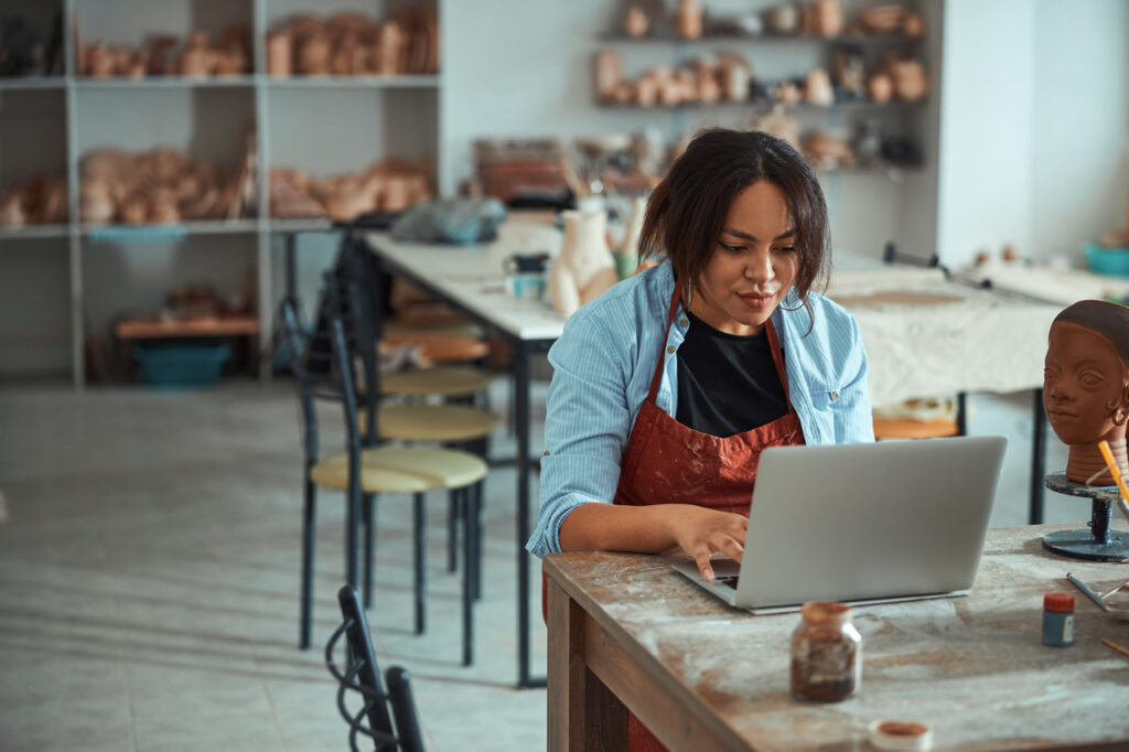 Woman sitting in a pottery room using a computer