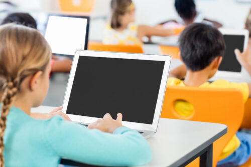 Young students use K-12 IT solutions and computers at a desk