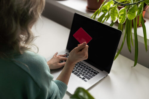 Woman sits in front of her laptop with a credit card