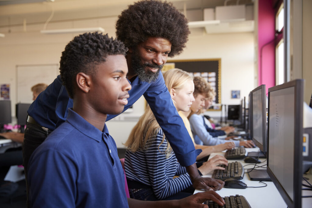 A school IT services professional helps students with computers