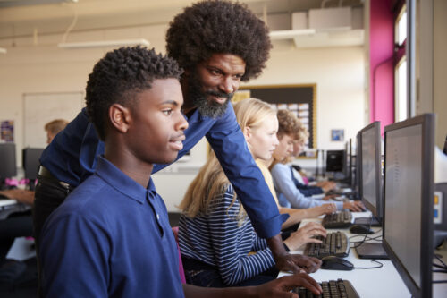 A school IT services professional helps students with computers